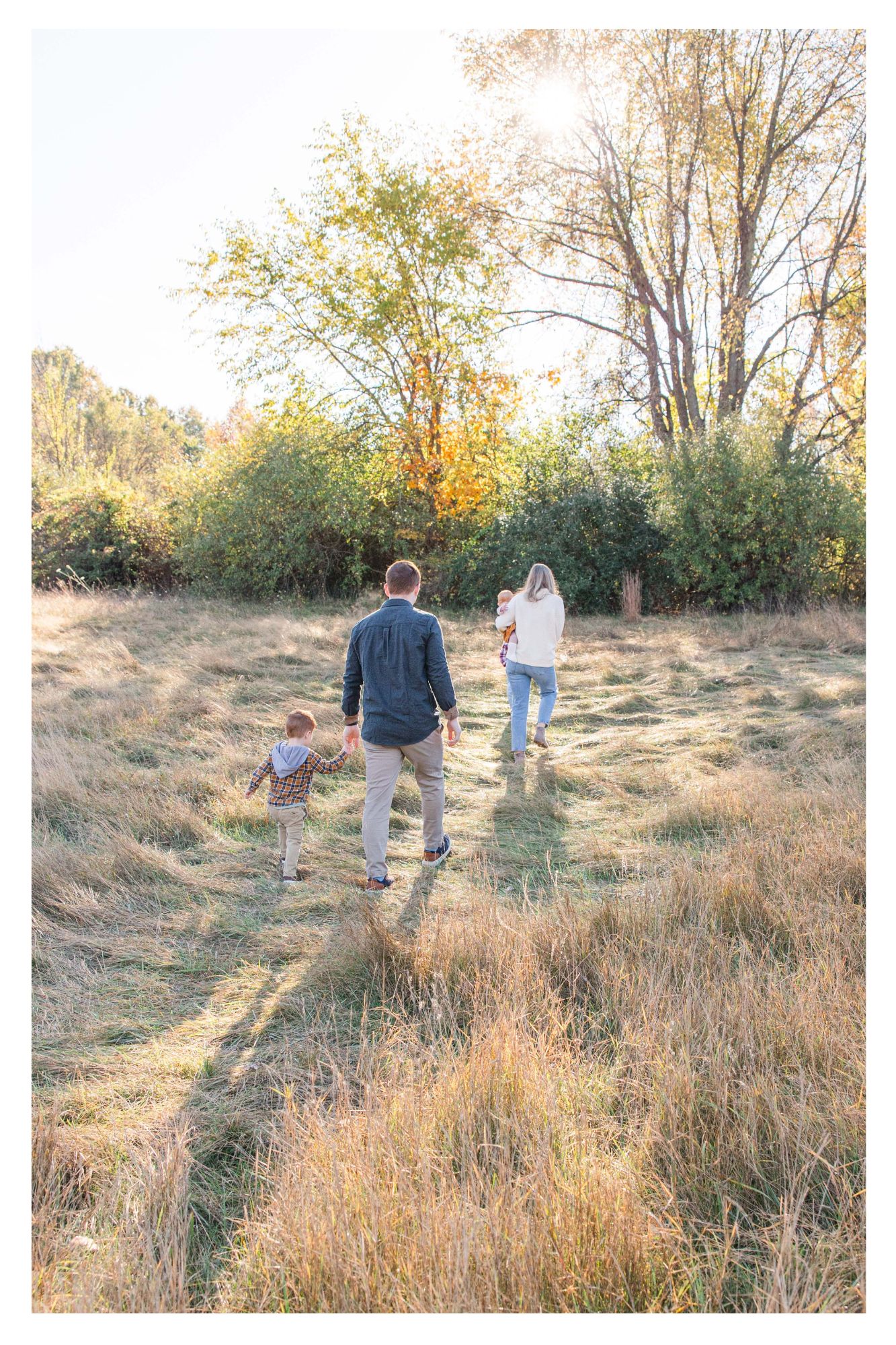 Family walking through early morning sunlight during a fall family session in Brighton MI