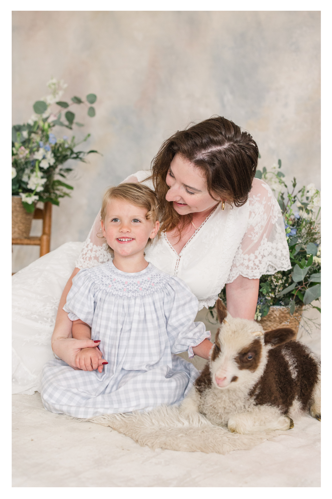 mother and child snuggle with a lamb during their motherhood portrait session in Mason MI